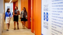 Three coworkers walk down a hallway together.