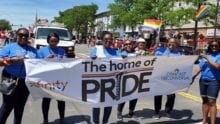 Pride parade with a banner being held by a few people