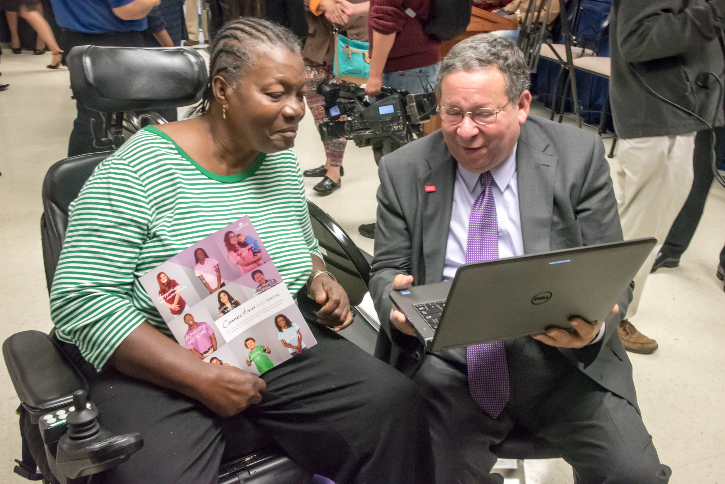 David L. Cohen presents an Internet Essentials participant with a laptop.